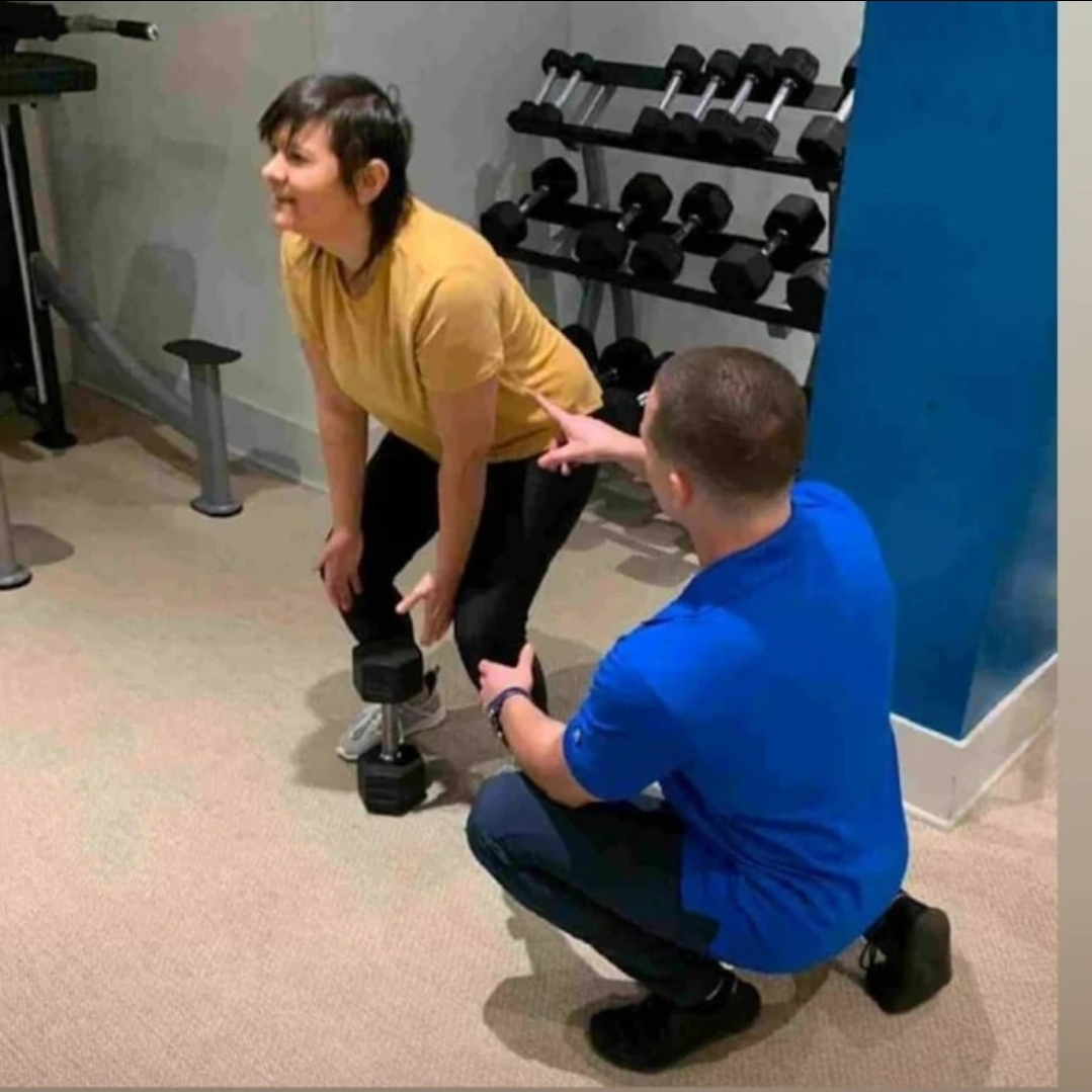 Jake coaching a client through a dumbbell exercise in the gym