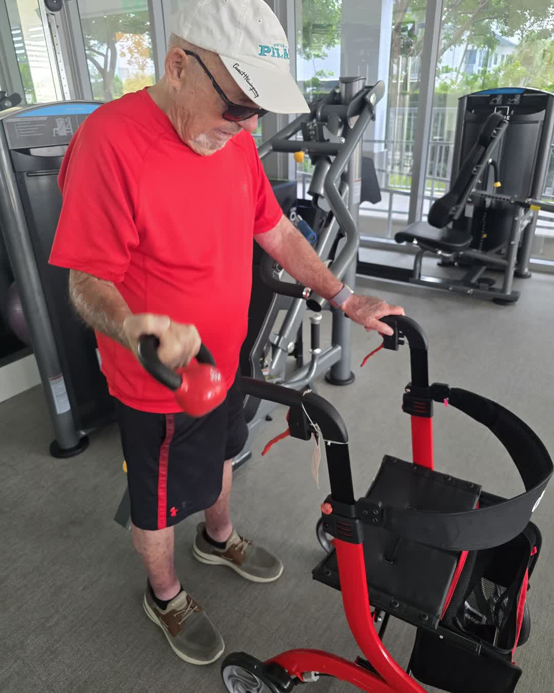 Jake's client Jerry doing a supported one-arm kettlebell curl while holding his rollator for balance